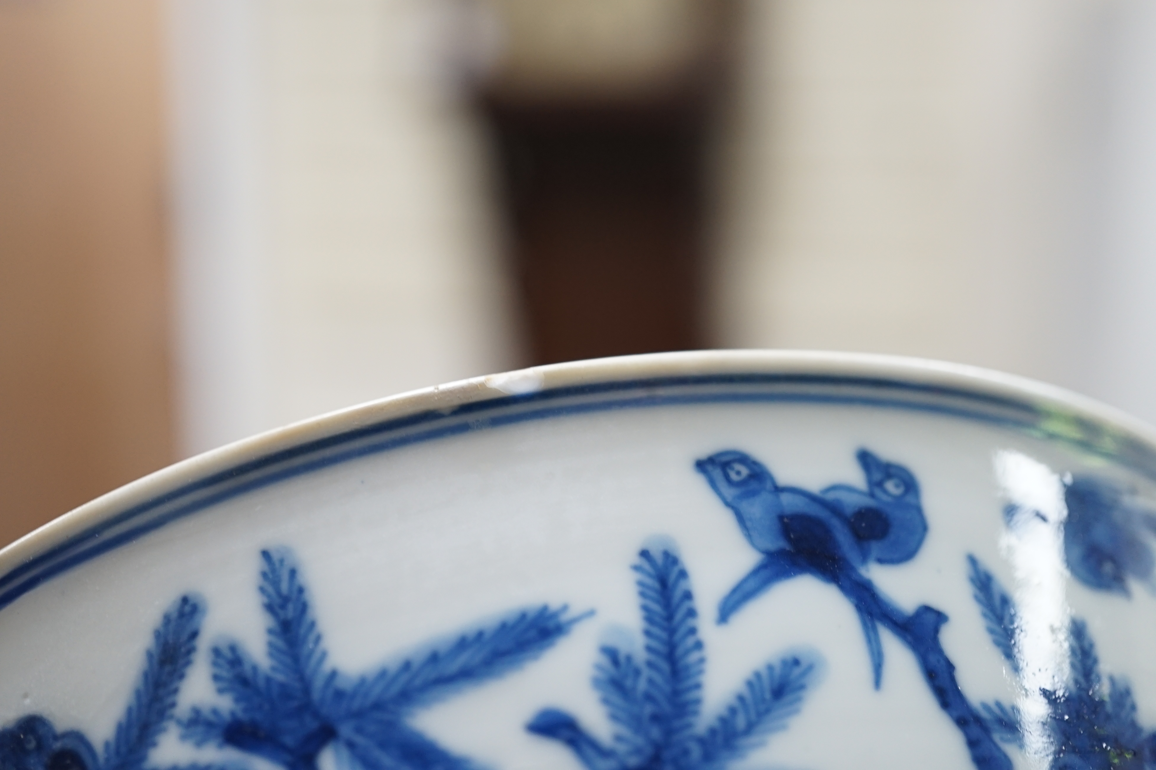 A near pair of Chinese blue and white ‘birds’ bowls, Kangxi period, one bowl restored
